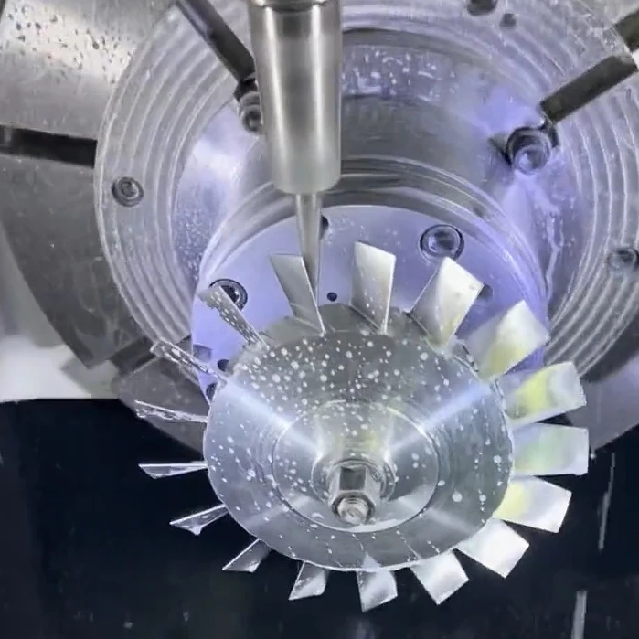 Milling tool machining the blades of a metal impeller held in a rotary fixture