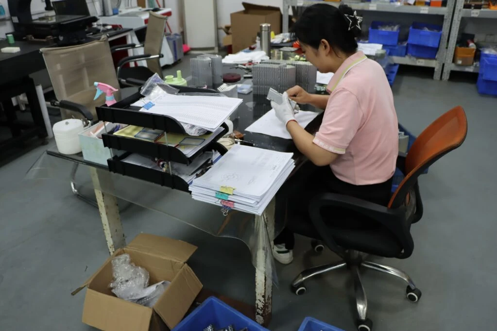 Quality inspector examining a metal component at a desk with inspection records and organized parts