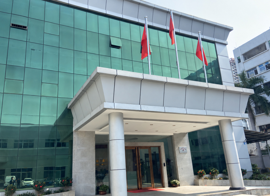 Factory building exterior with green glass facade, entrance canopy and flagpoles