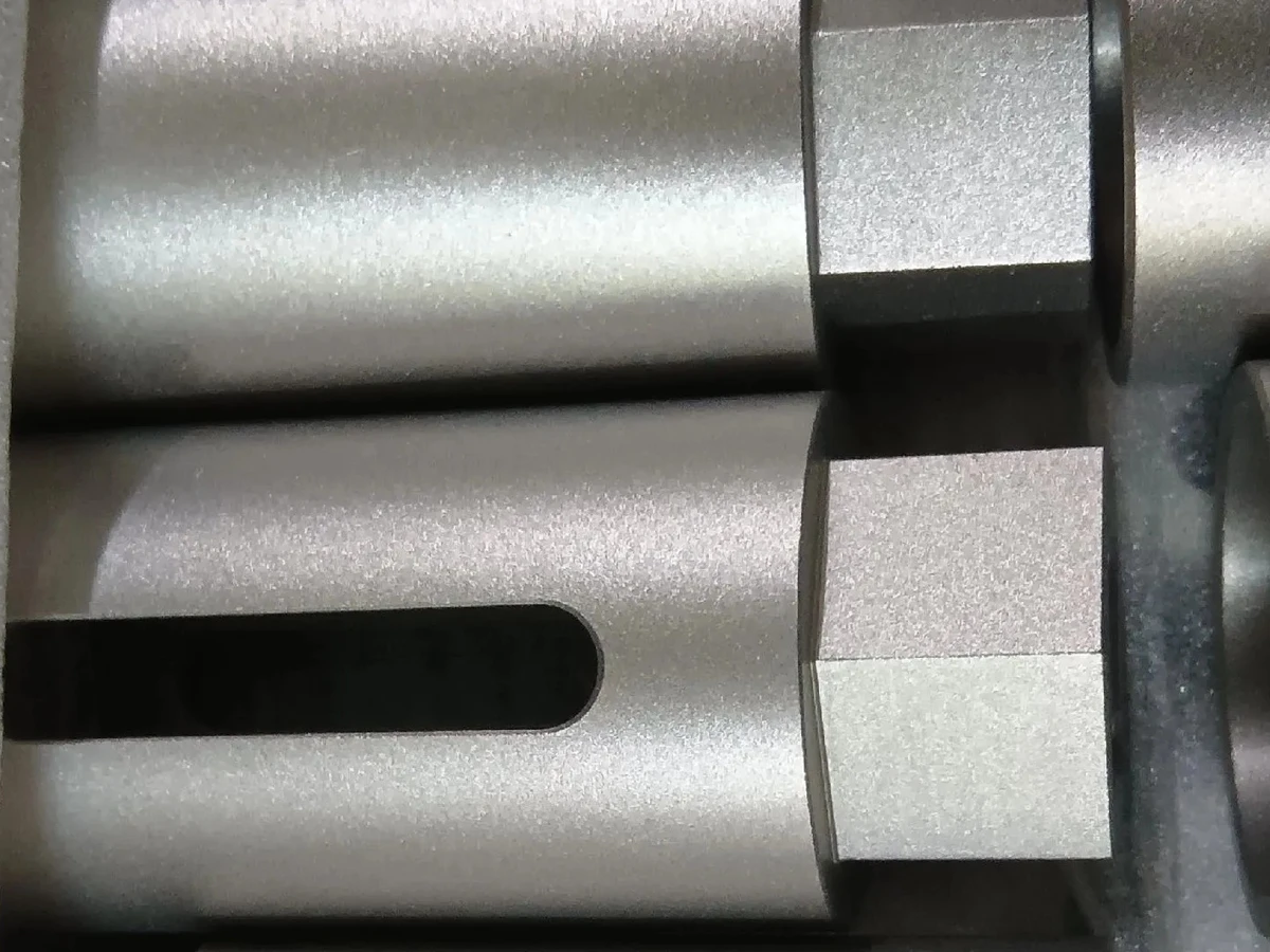 Matte-textured cylindrical metal components with flats and a longitudinal slot