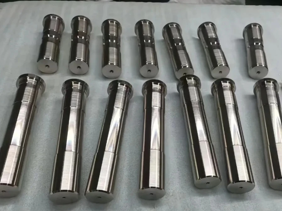 Nickel-finished metal shafts with stepped diameters arranged on a white sheet