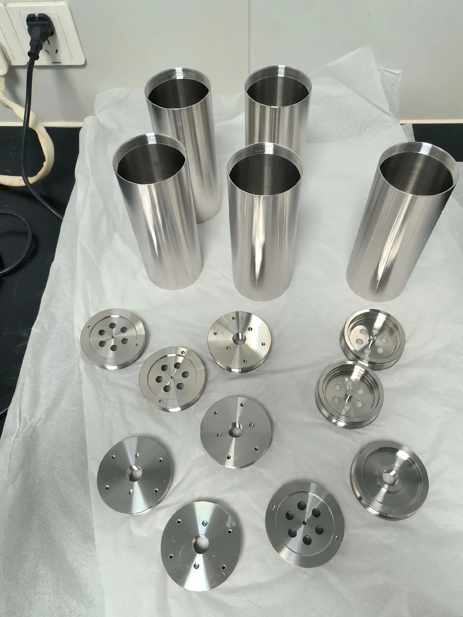 Stainless cylindrical housings and circular end plates arranged on a white sheet