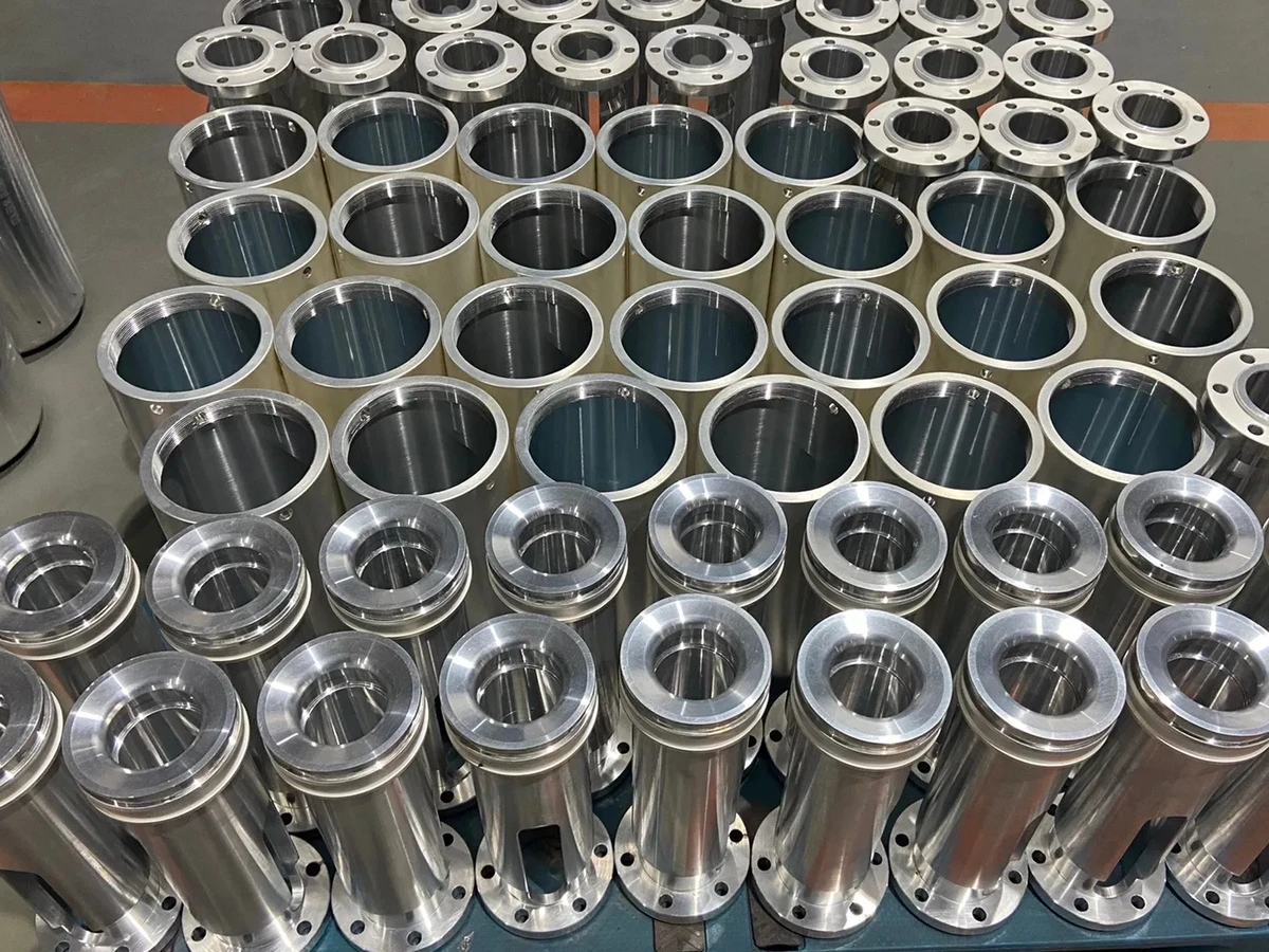 Silver-finished cylindrical components with bores and mounting flanges arranged in rows