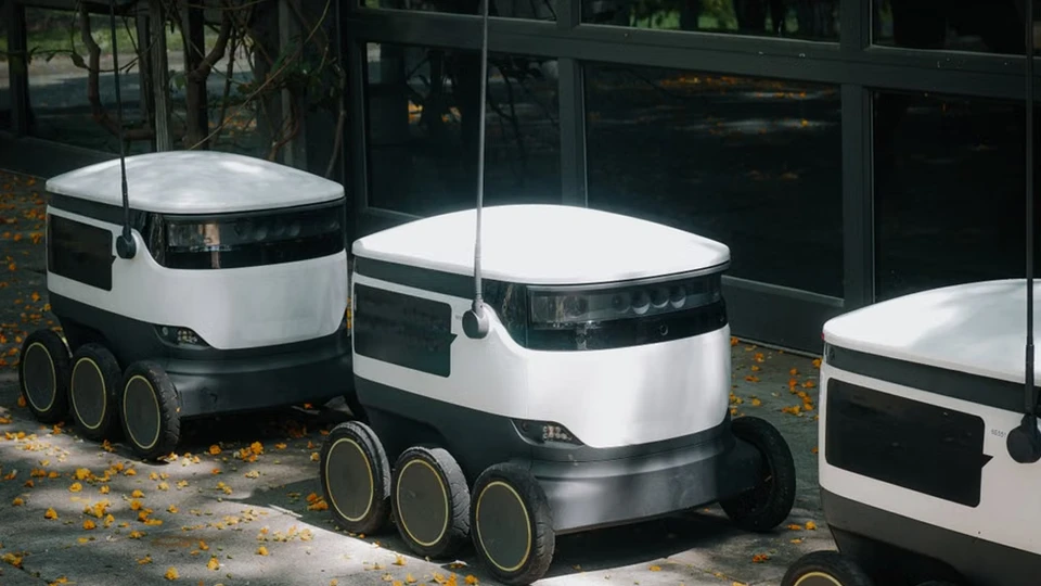 Autonomous wheeled delivery robots beside a building