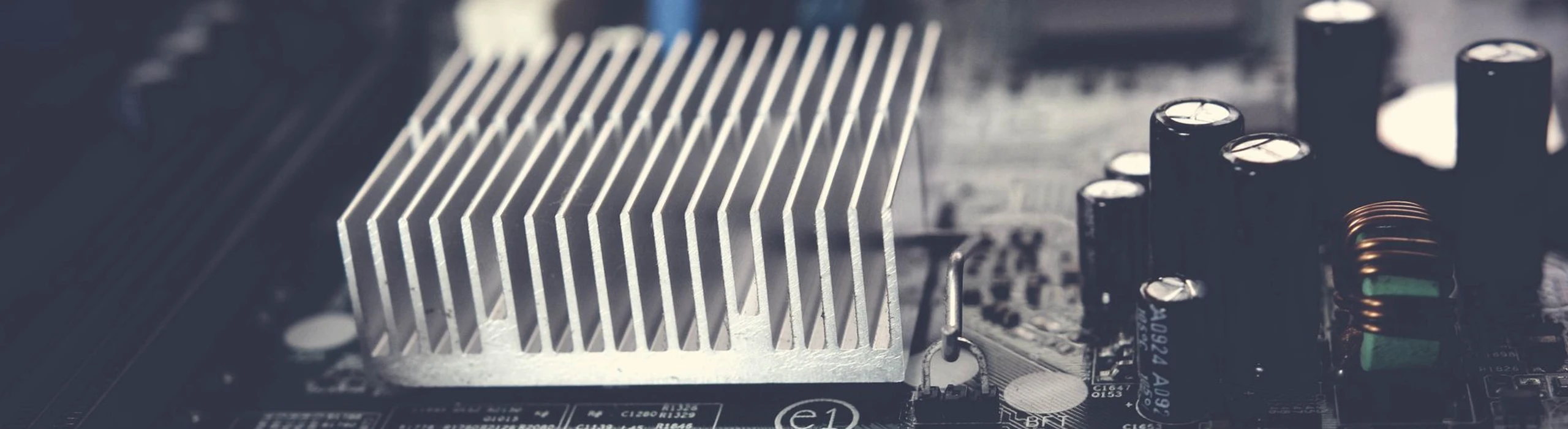 Aluminum finned heat sink mounted on an electronic circuit board beside capacitors