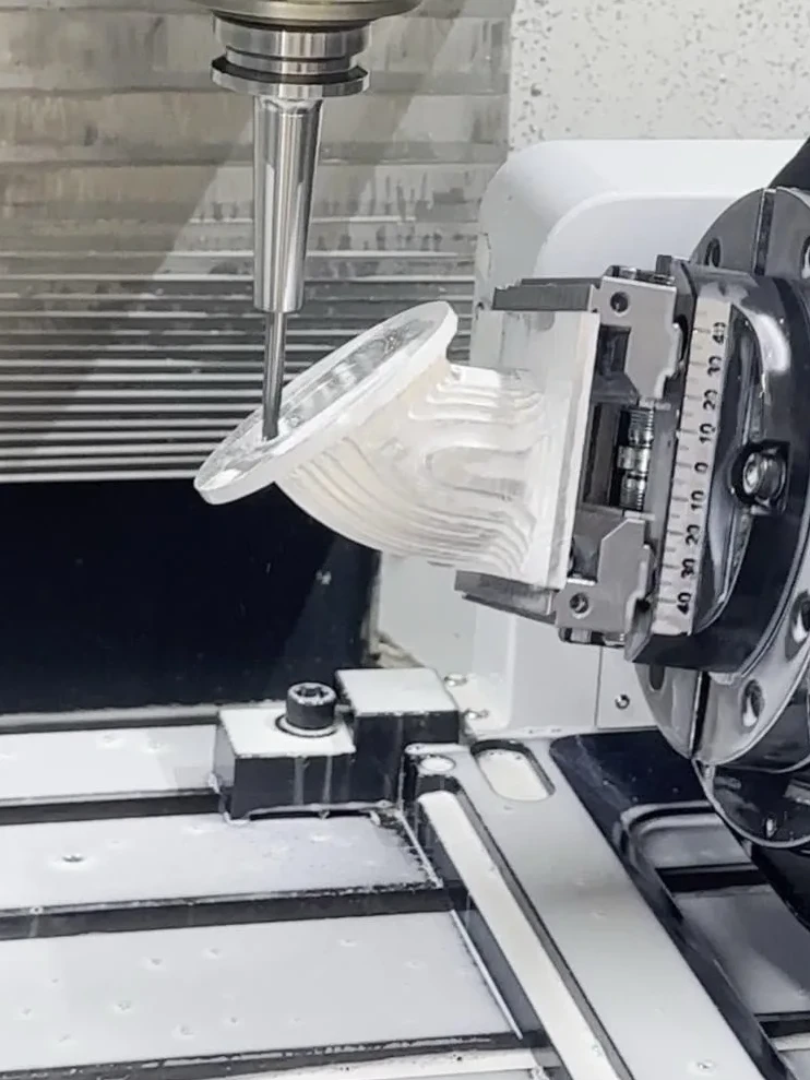 CNC milling tool machining a contoured metal component held in a rotary fixture