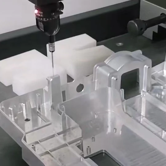 Coordinate measuring probe inspecting a milled metal housing with pockets, ribs and mounting features