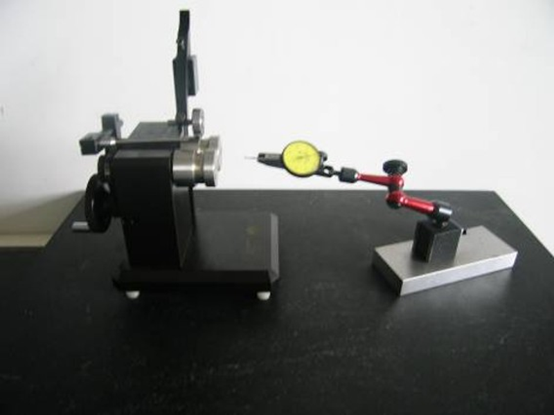 Concentricity and runout checking fixture beside a dial indicator on an adjustable stand