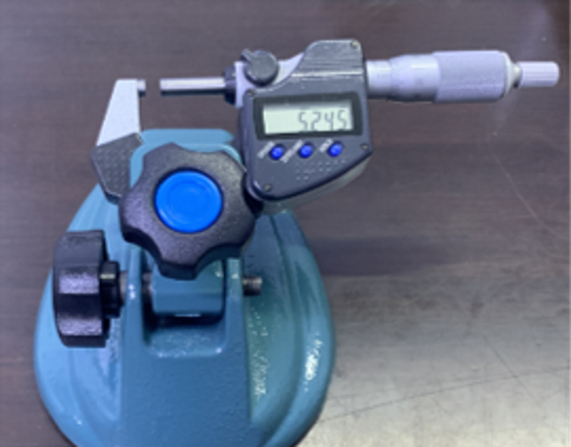 Digital outside micrometer held in a blue bench stand