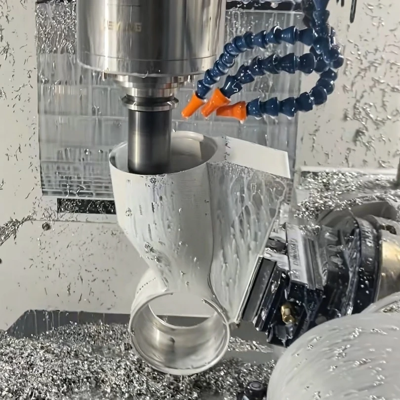 CNC spindle machining a hollow metal housing with intersecting bores inside a machine enclosure