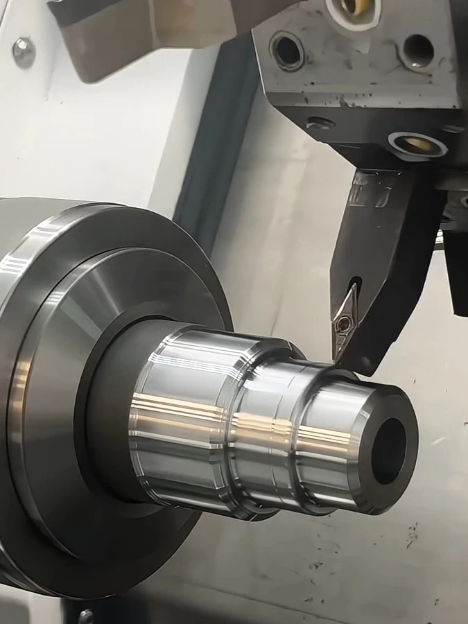 A lathe cutting tool turning stepped diameters on a hollow metal component held in a chuck